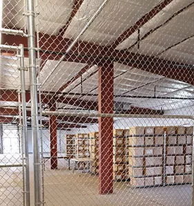 A warehouse secure storage fenced area with shelved boxes.