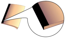 Bindery image showing what a tape bind looks like, piece of colored fabric tape covering the binding of the booklet from top to bottom.